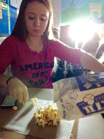 Junior Lexi Manker pours herself some popcorn during the movie.  Photo By: Grace Burns