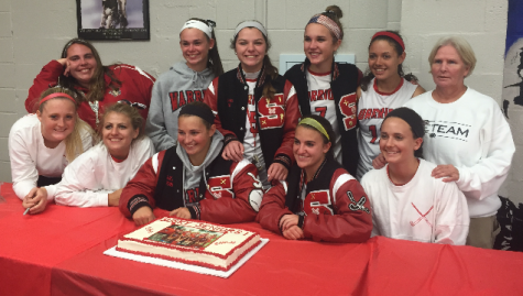 The field hockey seniors and Coach Sharon McLaughlin gather around their cake at the post game celebration. Photo by Addy Schefter.