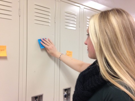 Junior and President of Aevidum Logan Garvey helps with putting the compliments on students' lockers. Photo By Grace Burns