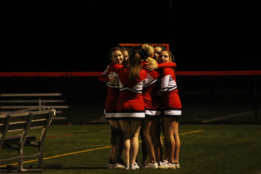 The cheerleading squad huddled while waiting to cheer. 