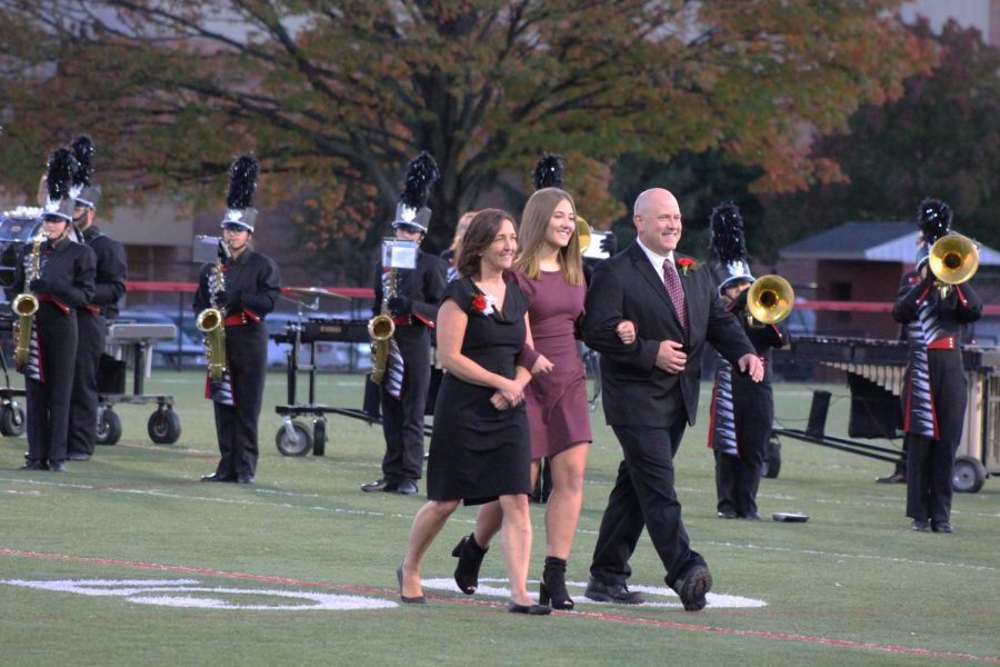 Senior Amber Bortner walks down the fifty yard line with her mother and father.