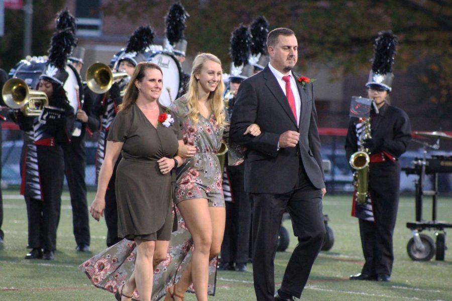 Senior Sarah Minacci walks with her parents during the Homecoming court recognition.