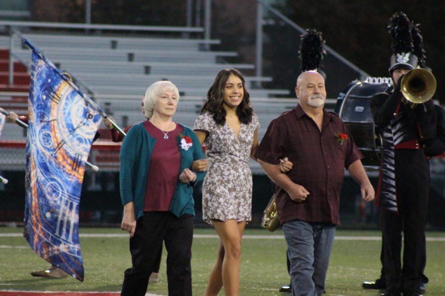 Senior Amaya Rutzel walks with her parents during the recognition. 