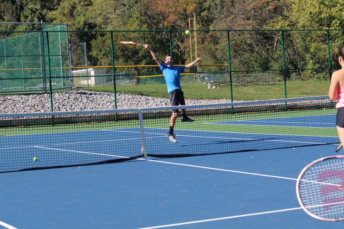 Senior Justin Field leaps up to hit the tennis ball. Photo by: Jade Reall 