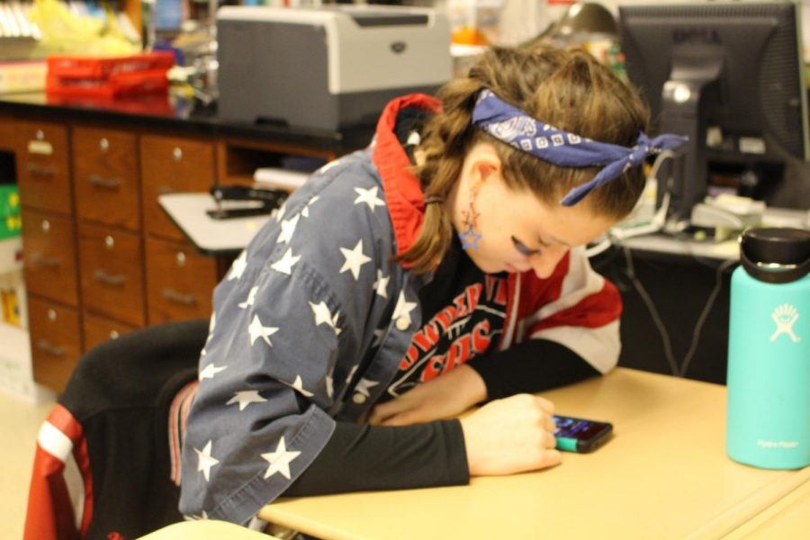 Senior Holly Bull checks her phone before class starts. Photo by Christopher Norris