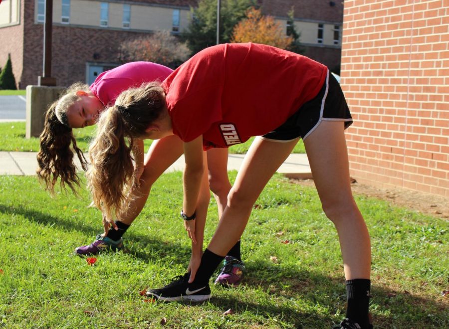 Freshman Desiree Witmer talks with sophomore Kylee Galante  as they warm up.