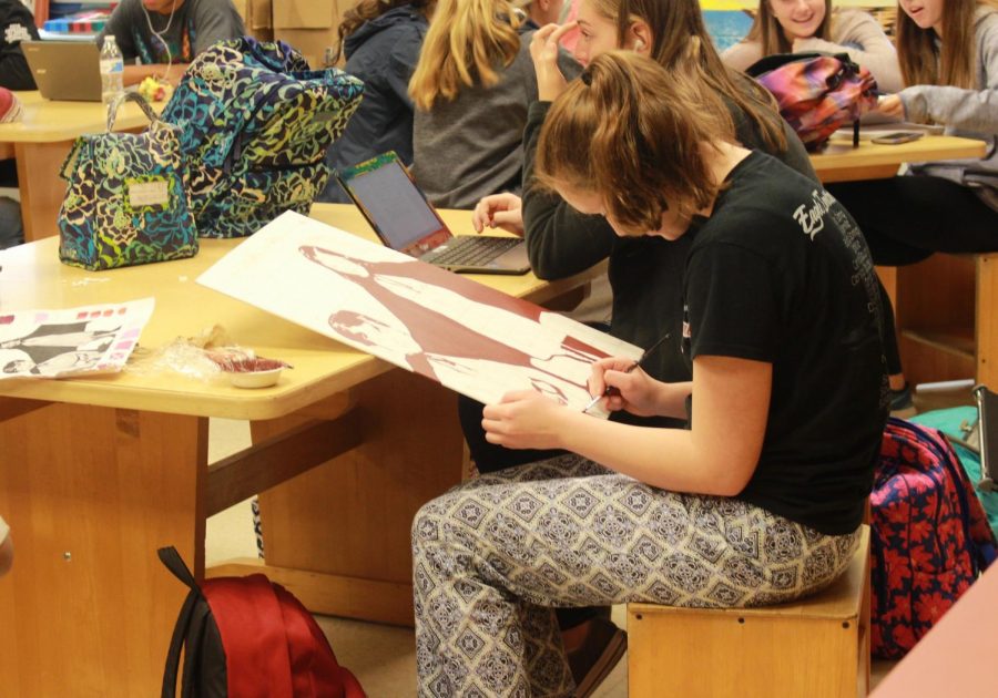 An art student works on a painting in her pajamas. 
