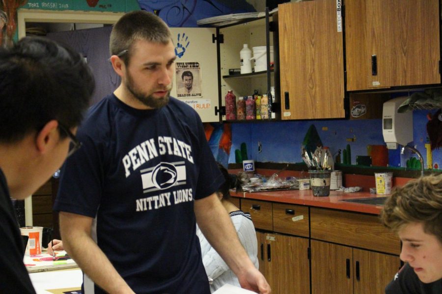Art teacher Wesley Myers talks with his students and wears a Penn-State shirt.
