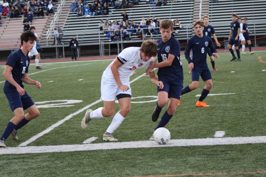 Senior captain Greyson Murray dribbles the ball down the field passing the Wildcat defender. 
Photo by Ava Holloway. 