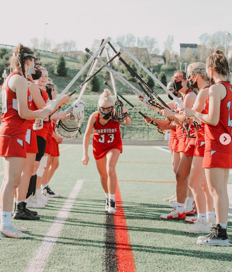 Senior midfielder, number 33, Kathryn Burke runs through the tunnel as they announce the starting lineup for the Warriors. Photography courtesy of @warriorgirlslax on Instagram. 