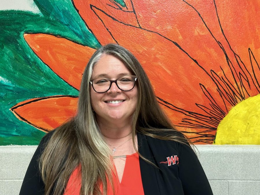 Ms. Smith stands in front of artwork for a picture. Photograph by Devin Gilbert.