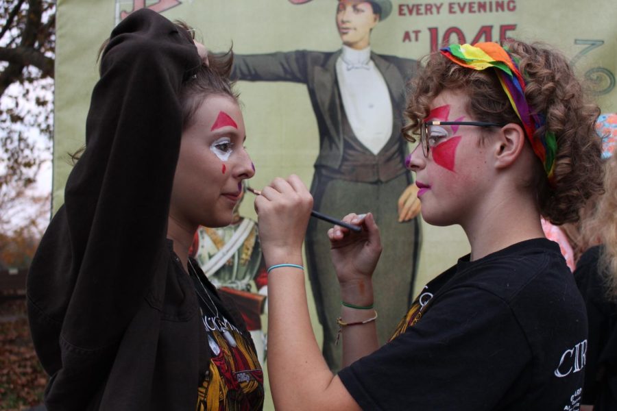 Junior Elaine Pulk paints the face of sophomore Megan Johannesen before October Fun Night. They were giving out candy at the band table. Fun Night is a ‘trunk or treat’ style event where kids dress  in their Halloween costumes and go around to each table to get candy.  Photograph by Katie Ball