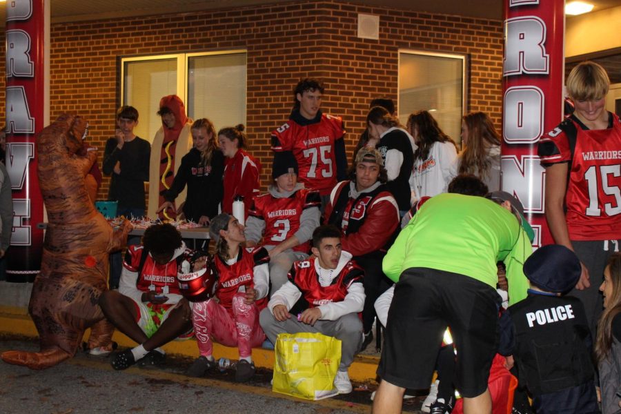 Members of the football team hand out candy dressed in their jerseys. Student Council organizes the event and collects canned goods for a local food pantry. This year more than 200 cans were donated. Photograph by Katie Ball
