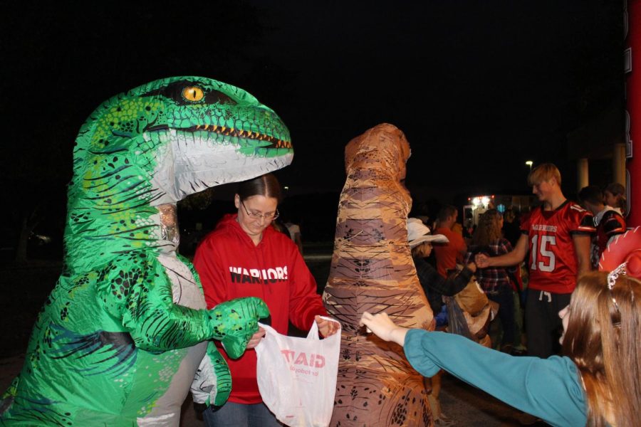A trick-or-treater dressed in an inflatioble dinosaur costume collects candy during October Fun Night. Inflatable costumes were a big hit this year. Photograph by Katie Ball