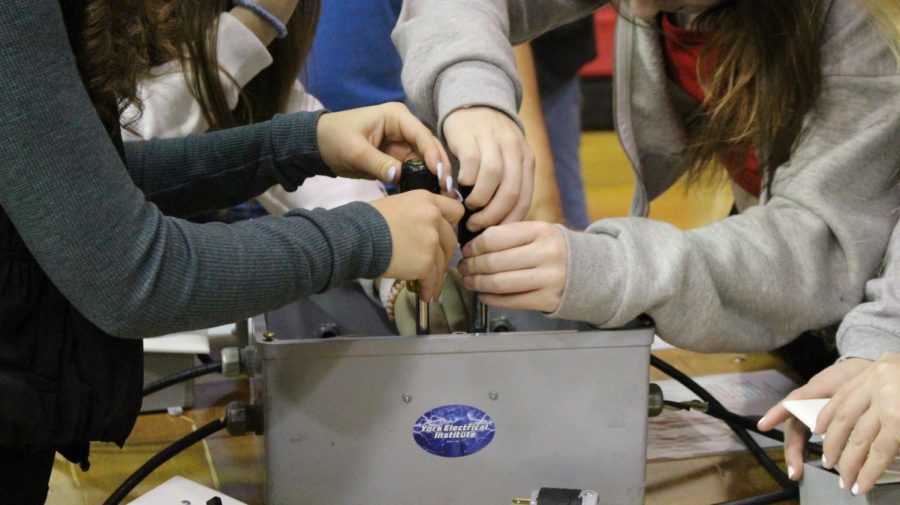 Students work together to wire a circuit at the electrical station. 
Photograph by Kate Ball