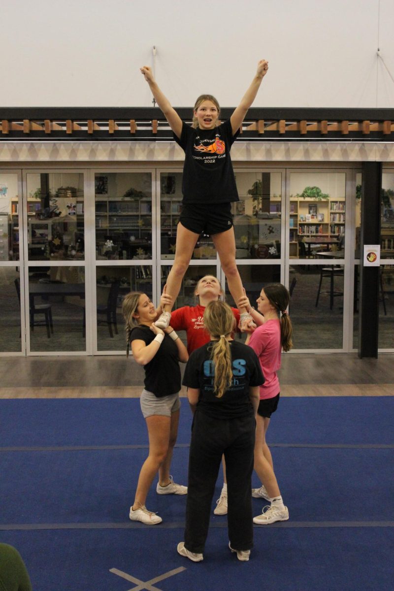 Junior Cassidy Derkosh is supported by several teammates as part of the cheer routine. The team works hard to communicate effectively when things go wrong.  We all understand that it is truly a team effort, Wilson said. In order for stunts or anything to work we must all work together. If one person can not do their job it restricts the entire team. We have an understanding that we either fail or succeed together as a team. No one is by themselves. We are a very understanding and respectful team. We all listen to each others opinions/input, and if there is an issue we are able to civilly talk about what is going wrong and try different solutions to enable us all to accomplish our goals. Most of the time there is more than one problem in a stunt, and it is never solely one persons fault. Having so many different factors in a group of girls leaves an abundance of room for improvements and changes that might for an unknown reason just work better. Photograph by Natalie Womack