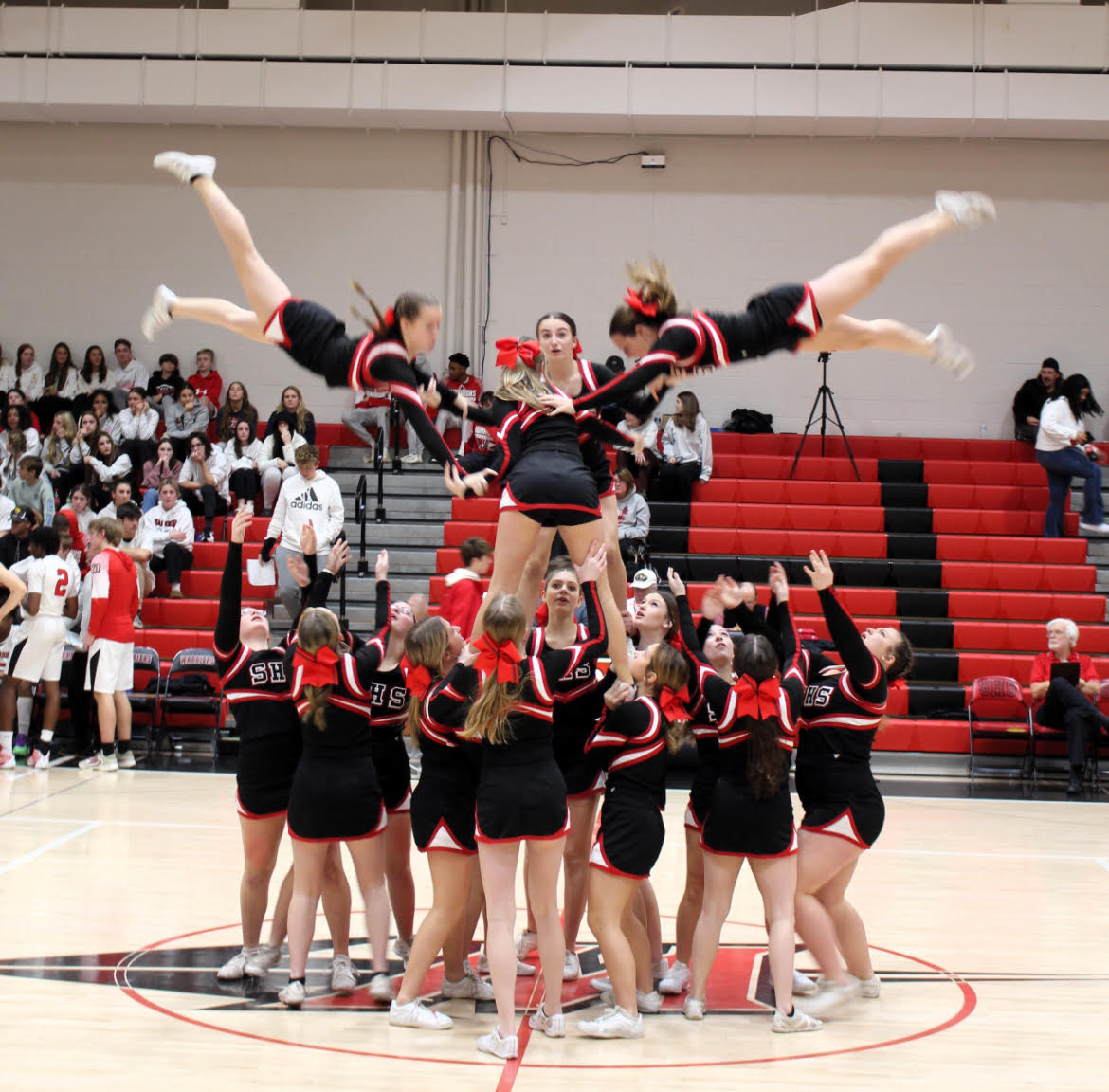 With blood rushing through their veins, making sure no one falls, the cheer team carefully and enthusiastically throws the cheerleaders into the air during their  routine at a boys basketball game.  Photograph Courtesy of Joce Sterman