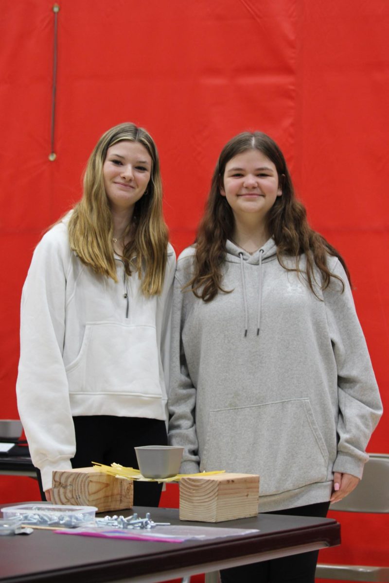 Freshmen Madison Chopper and Camryn Walsh demonstrate their bridge made of pasta. “We were asked to build a bridge out of pasta. It was designed to hold [the bolts].” Walsh said. 

