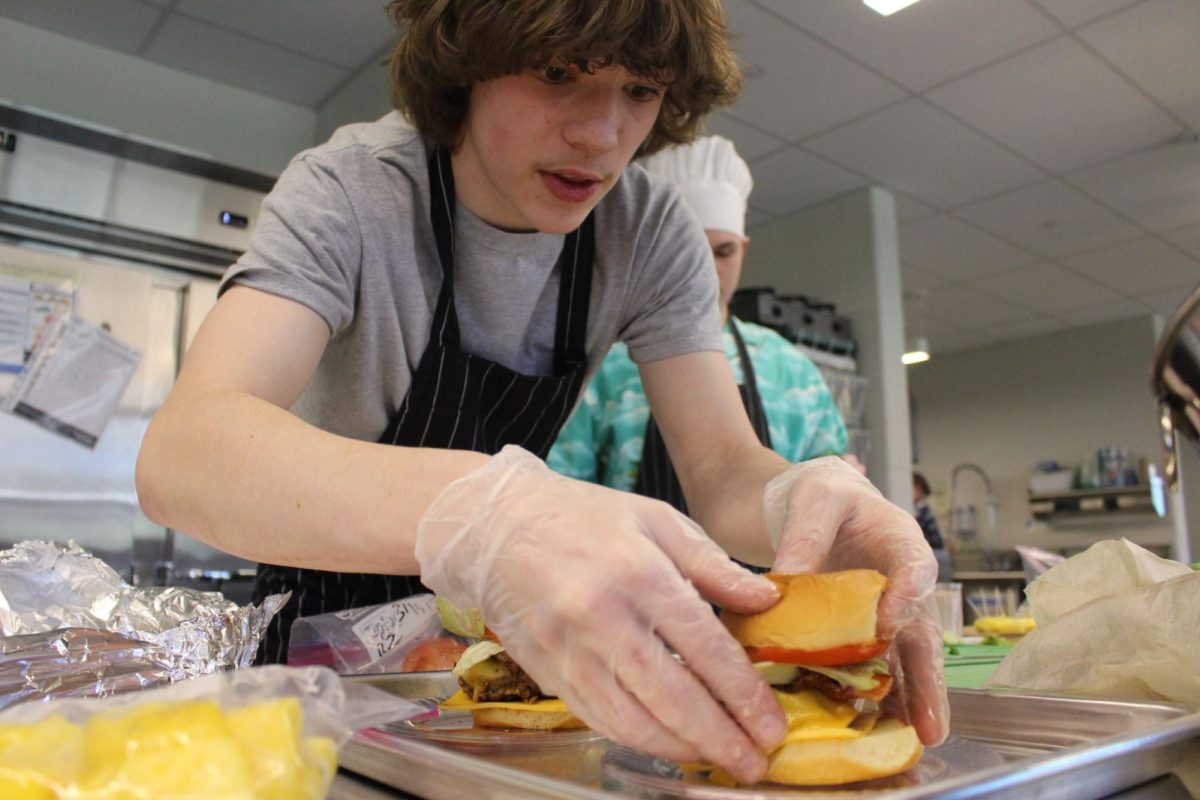 Sophomore Riley Heinbaugh puts the finishing touches on his team’s  burger with only a minute and a half to go.  Photograph by Josie Witsik
