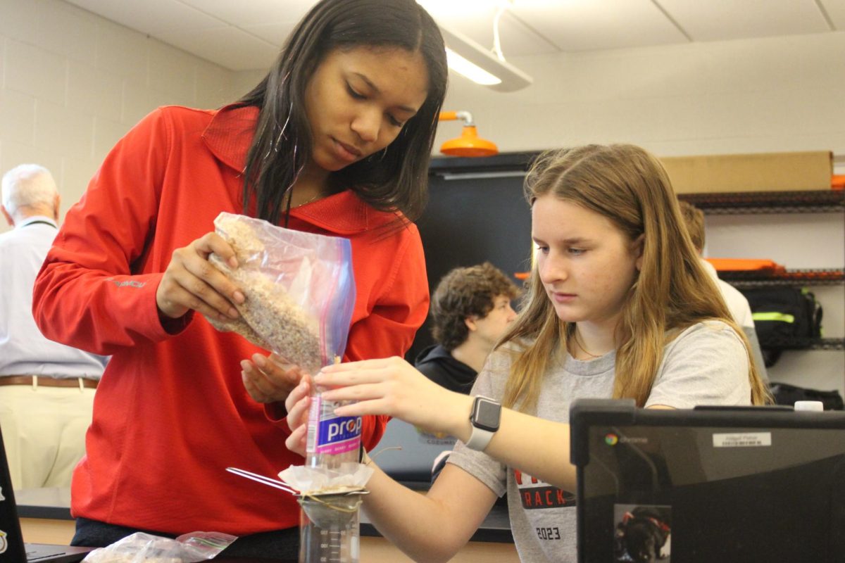 Junior Zoey Jones and senior Abigail Fisher construct their water filter using coffee filters, sawdust, gravel, and other materials. “Sawdust is really good for… soaking up all the big clumps and everything and thats… what the pebbles are in,” said Fisher. “We really want to get the sand and sediments out of there and we;re just going to be left with the water.” Photograph by Lachlan Gemmill-Edwards
