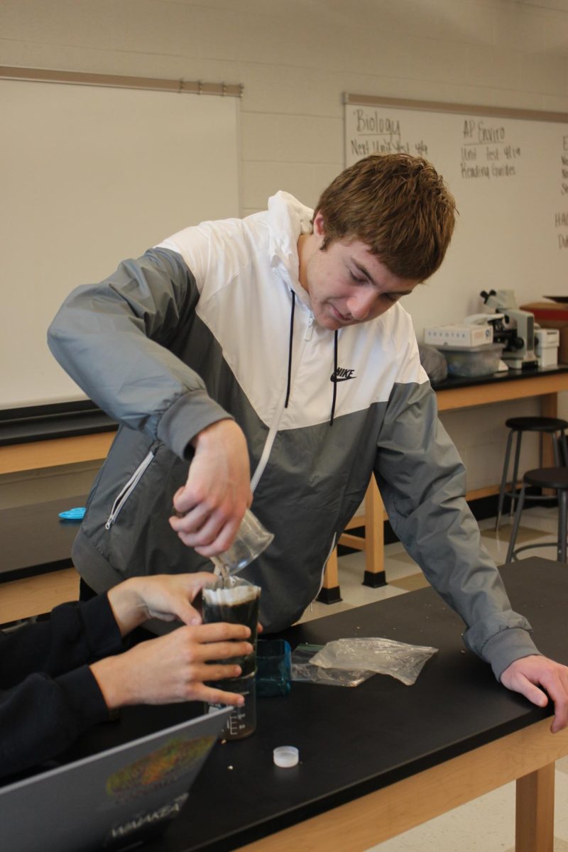 Senior Josh Connors pours the dirty water into his group’s water filter. Students aren’t just aiming to have the cleanest water, but they are also aiming to get the water through the filter as fast as possible. “Time is money, product is money. All that kind of resources is money.” said Worley “They have to get ‘x’ amount of liquid out of it for grading basically.”  Photograph by Lachlan Gemmill-Edwards