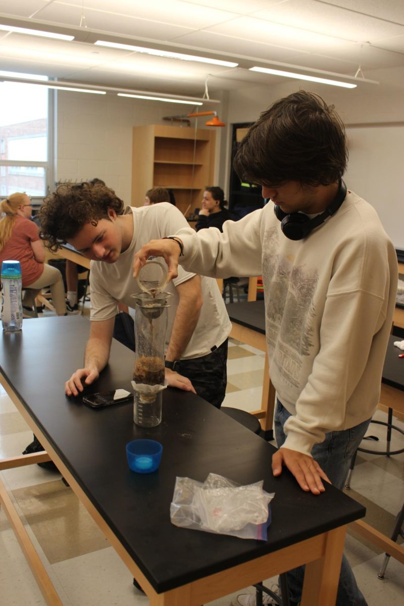 Seniors Stephen Mayoryk and Devin Gilbert pour the dirty water mixture into their water filter. “[The students] have to build their apparatus to try to get the cleanest water they possibly can.’ said Worley. “Then I just throw a bunch of stuff into the blender and give them dirty water and then they have to get it as clean as they possibly can.” Photograph by Lachlan Gemmill-Edwards