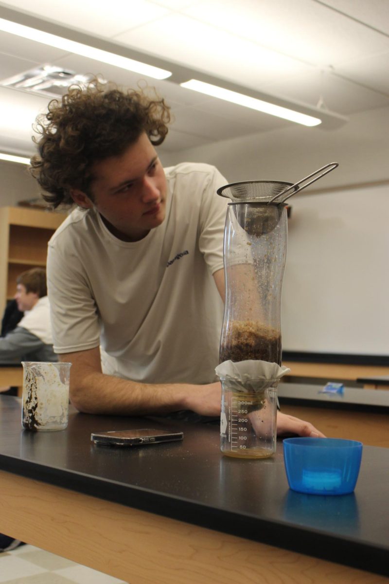 Senior Devin Gilbert watches his group’s water filter. The water gathering in the beaker is the water that the groups will submit for review to Worley and Holley. Photograph by Lachlan Gemmill-Edwards