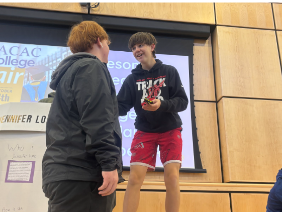 Freshman Mason Buckley gives a fellow student his presentation about Jennifer Lopez and showed his mini model for the Hispanic Heritage Fair hosted by the Spanish classes on October 10 in the commons area of the high school. “During the project, I learned new fun stuff,” Buckley said.  ¨My partner was great, he helped a lot with the project. It was really fun and I would do it again in a heartbeat.” Photograph by Josie Witsik
