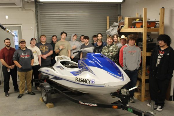 Auto Club members stand together behind a jet ski. Photograph by Nathan Freeser