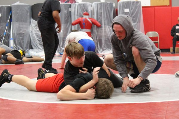  Senior Dawson Zorbaugh helps sophomores Joshua Crue and Eli McHale on their half-nelson technique. Zorbaugh has been a member of the wrestling program for all four years of his high school career. Photograph by Bella Guarnera
