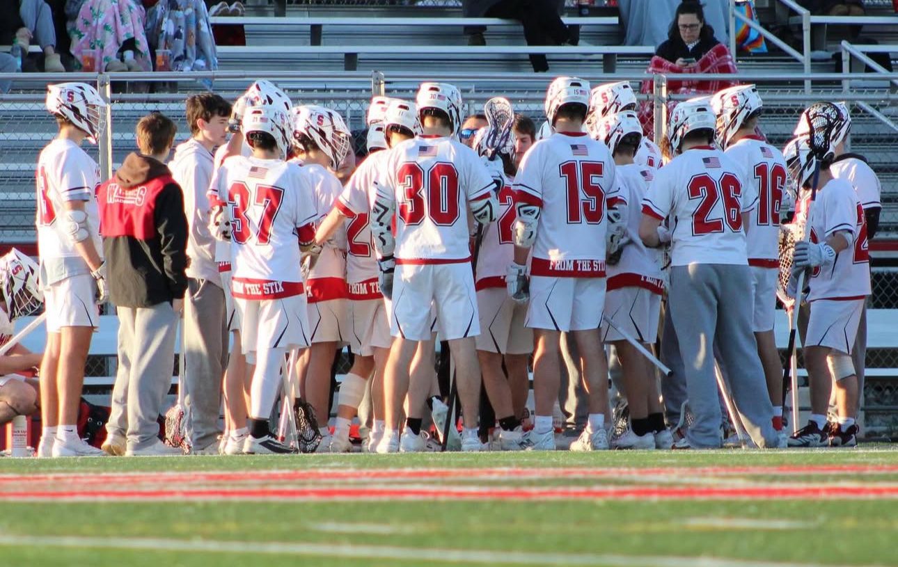 Boys Lacrosse team embracing each other after a win