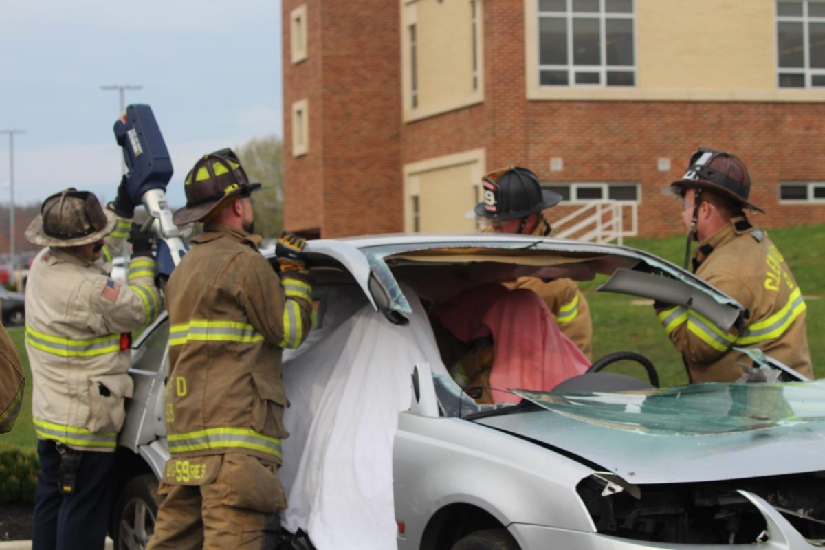  Glen Rock Firefighters hold the roof of the car as another uses the “Jaws of Life” to  remove it to gain better access to the ‘patients.’ Rescue personnel put blankets or towels over their patients’ heads to protect them from glass or any other debris.
Firefighters remove car roofs after accidents to create access for trapped victims, allowing EMS personnel to reach and treat them quickly. Photogrpah by Joise Witsik

