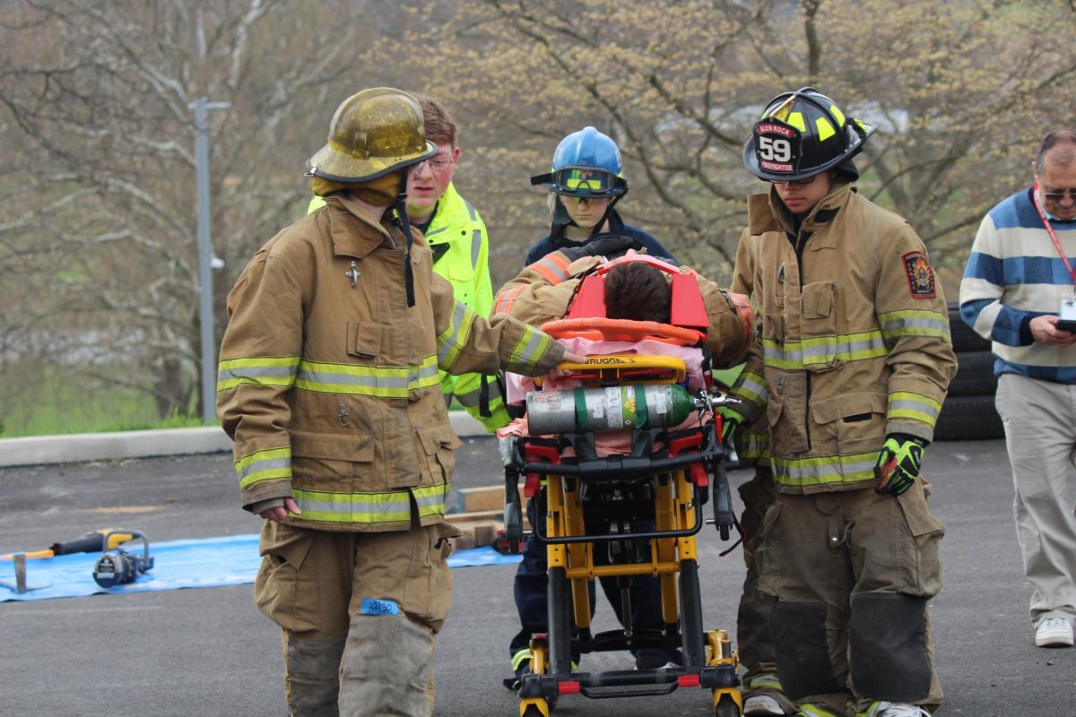 Firefighter and E.M.T Students use a stretcher to move their ‘patient’ to the ambulance. Stretchers provide a safe, stable, and efficient way to move patients who may be injured, incapacitated, or require careful handling during Transport.to prevent further injuries. Photograph by Peyton Elmore 