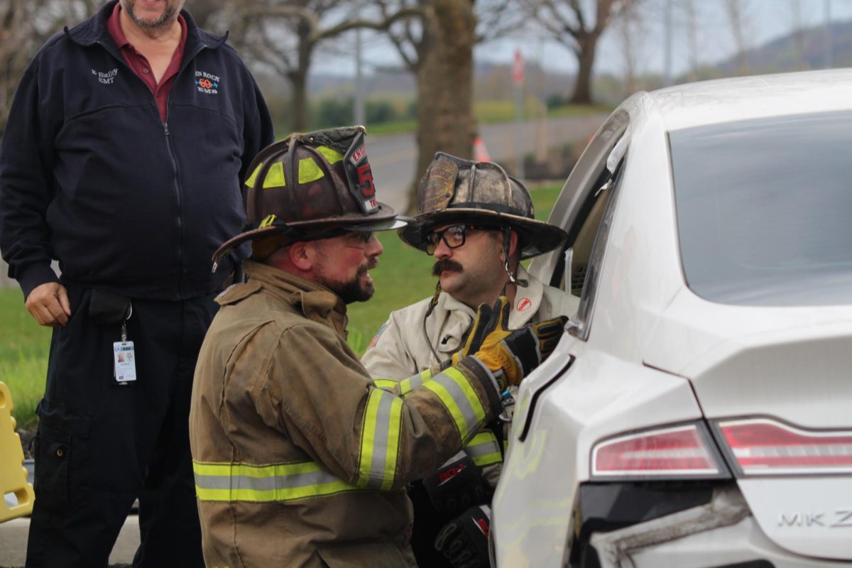  Two Glen Rock firefighters explain to E.M.T. students about what they need to do in a situation like this when it comes to rescuing patients from a crash. Firefighters' equipment plays a crucial role in protecting them from hazards like heat, flames, and toxic smoke. A key piece of equipment is turnout gear which provides thermal and physical protection. photographed by Peyton Elmore 
