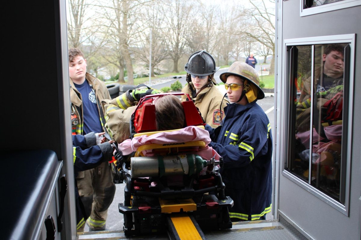 E.M.T. students and Glen Rock firefighters lift the stretcher with a ‘patient’ into the ambulance. EMTs use stretchers to safely and efficiently transport patients, especially in emergency situations where speed and stability are critical. Photograph by Josie Witsik