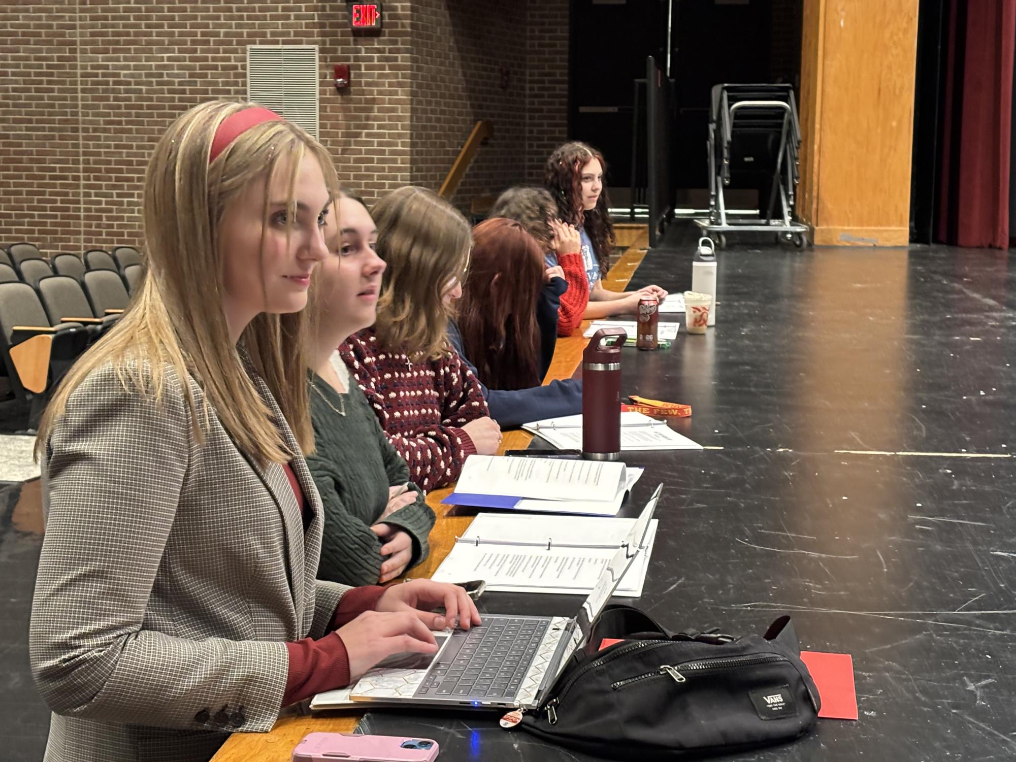 Sophomore Ella Miliauskas, junior Kaitlyn Staub, junior Isabella Quintillion, junior Alicia Baker and seniors Kiley Herzog and Ava Miliauskas watch the actors as they act out the “food critic” scene. Junior Charlie Schaffer co-wrote this story with Ella Milauskas. “[It took] about a week to write, and almost a year to edit by Ella,” Schaffer said. “There were many causes and sometimes when we solved one issue another one would pop up and It overall was a very busy year.” 
Photograph by Rhys Sanders