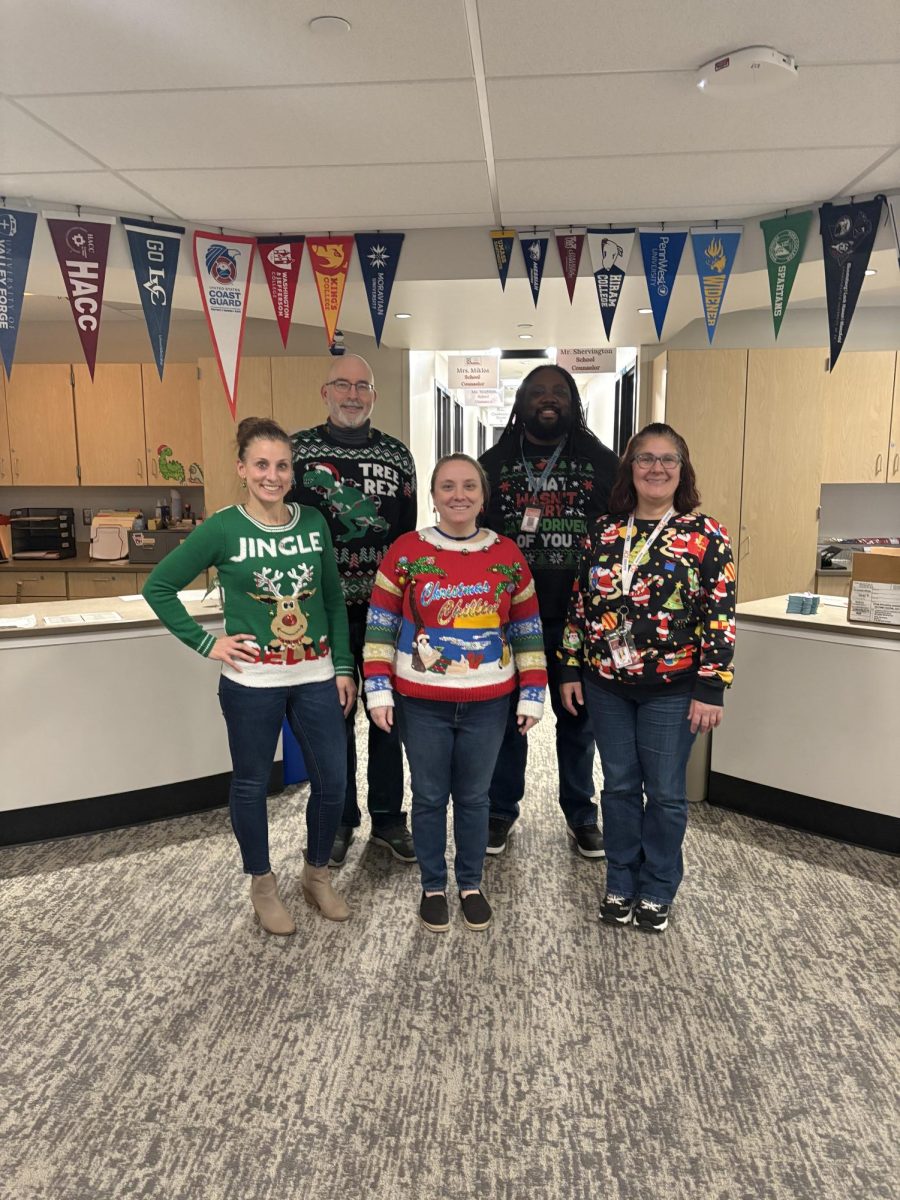 School counselor Kate Miklos, College and Career Coordinator Matthew Amberman, counseling office assistant Theresa Slemp, school counselor Matthew Shervington,  and school counselor Dr. Billie Jean Miller model their holiday-themed sweaters for spirit week. The counseling staff dressed up every single day of the spirit week to spread holiday cheer. Including Shervington dressed as the Grinch for ‘Winter Character Day’. Photograph by Caroline Simpson