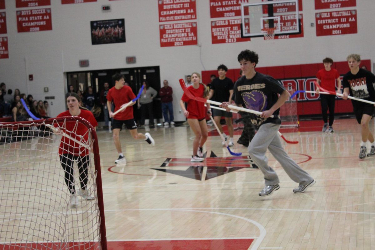 Senior Danielle Lavery and junior Connor Eckert pursue the ball during the championship floor hockey game held during the all-school pep rally on Feb. 13. The final four teams of the Winter Olympics tournament hosted by Student Council competed during the rally. The Winter Olympics took place throughout the month of January and culminated with the final games at the pep rally. “Our team was pretty confident going into the rally,” Lavery said. “We were definitely a little nervous walking onto the gym floor  since we went to finals last year and lost but this time we felt more confident and ready to win.” Photograph by Peyton Elmore