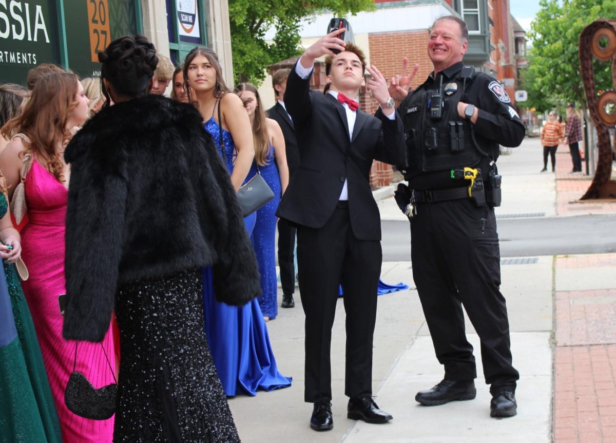 Calleigh Ambrose’s date takes a photo with School Resource Officer Darryl Smuck while standing in line, waiting for the doors to open. “Getting pictures I feel like is the biggest part…I want to be able to have them for the future,” junior Jenna Lynch said. Photograph by Lucy Wherley