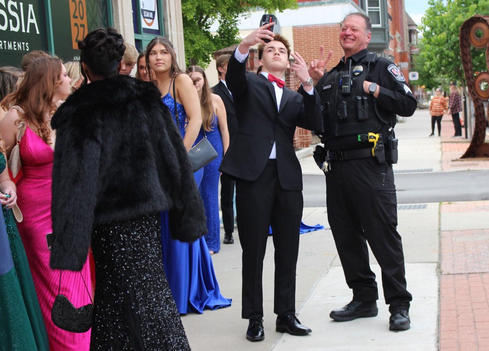 Calleigh Ambrose’s date takes a photo with School Resource Officer Darryl Smuck while standing in line, waiting for the doors to open. “Getting pictures I feel like is the biggest part…I want to be able to have them for the future,” junior Jenna Lynch said. Photograph by Lucy Wherley